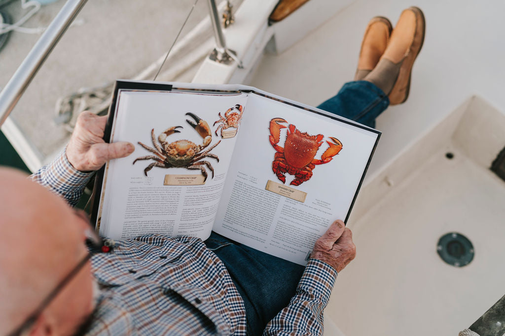 Reading an open Southern Seafood book beside the water